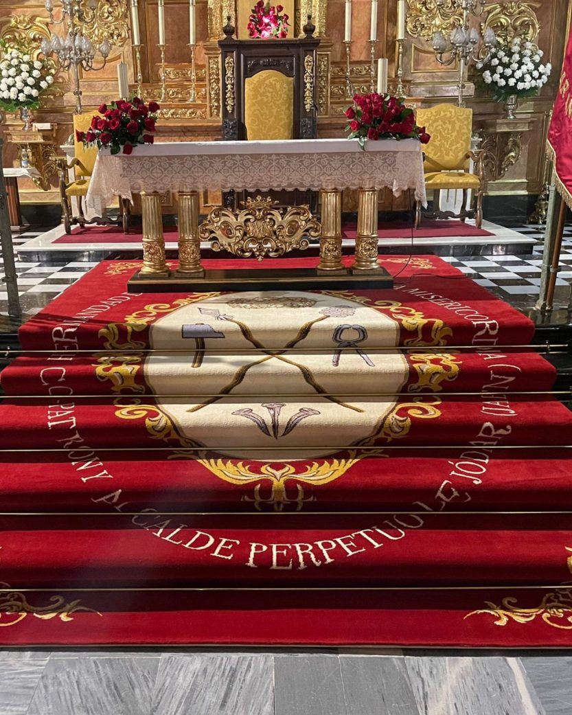 Alfombra de una hermandad, luciendo sobre las escaleras de un altar