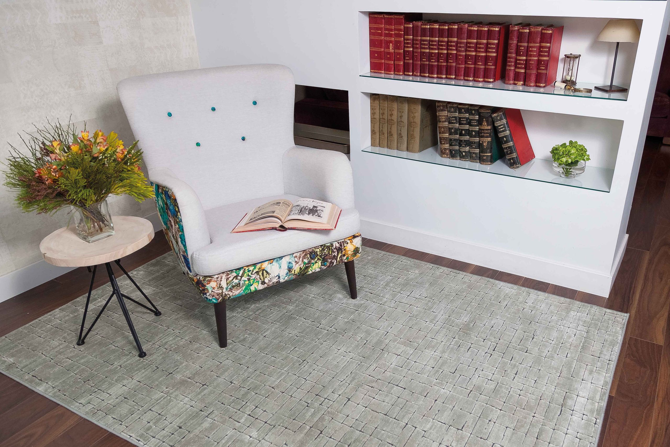 Ambiente decorado siguiendo las directrices del neurointeriorismo, con una sala de lectura, con sofá, mesita, alfombra y estantería con libros